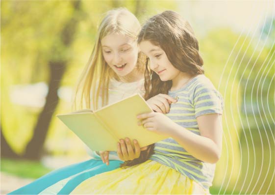 happy girls reading book outdoors