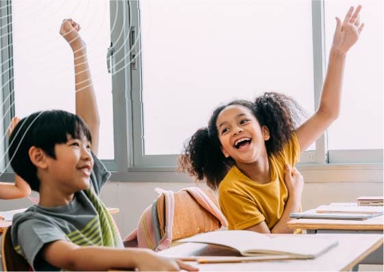 two students laughing while raising their hands